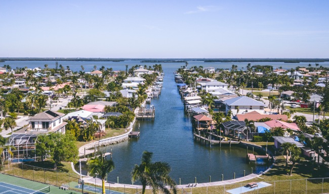 Aerial view of a waterfront neighborhood in Southwest Florida featuring palm trees, canal-front homes, and scenic waterways near Estero Vista apartments.